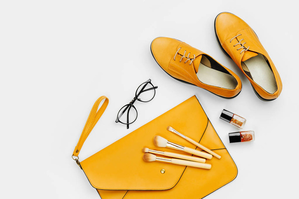 Flat lay of female fashion accessories, shoes, makeup products and handbag on orange colors. Beauty and fashion concept - Foto, Imagem