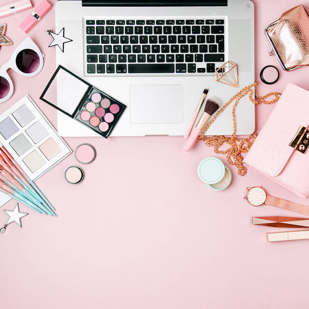Fashion blogger workspace with laptop and female accessory, cosmetics products on pale pink table. flat lay, top view - Fotoğraf, Görsel