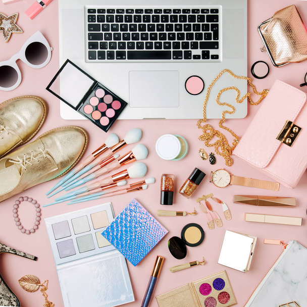 Fashion blogger workspace with laptop and female accessory, cosmetics products on pale pink table. flat lay, top view - Foto, immagini