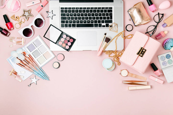 Fashion blogger το χώρο εργασίας με laptop και γυναικεία αξεσουάρ, καλλυντικά προϊόντα σε απαλό ροζ πίνακα. επίπεδη lay, κορυφαία προβολή - Φωτογραφία, εικόνα