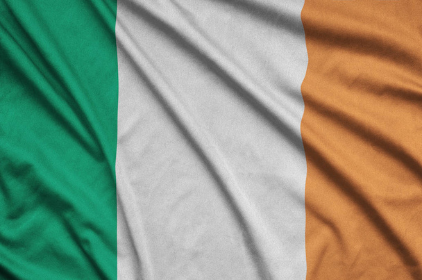 Írország lobogója alatt sok ráncok sport szövet szövet ábrázolja. Sport csapat integetett zászló - Fotó, kép