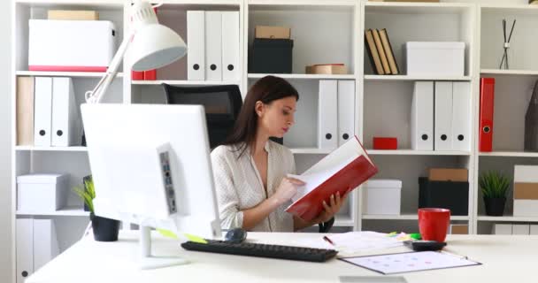 Kobieta w białej bluzce czytanie dokumentów w folderze - Materiał filmowy, wideo