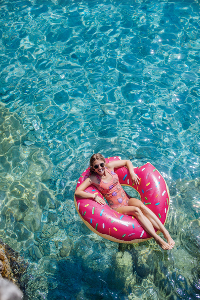 Mujer bonita acostada en anillo flotante en el mar Mediterráneo y disfrutando de tomar el sol
. - Foto, Imagen