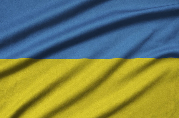 ウクライナの国旗は、多くのひだを持つスポーツの布生地に描かれています。スポーツ チームを振ってバナー - 写真・画像
