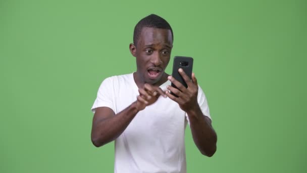 Young African man looking shocked while using phone - Video