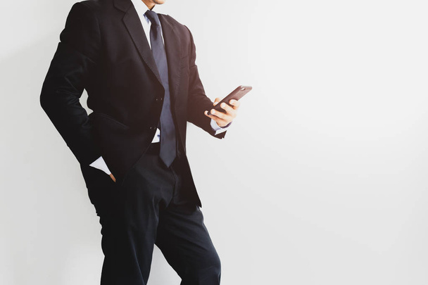 Businessman using cell phone standing on front of white background - Fotó, kép