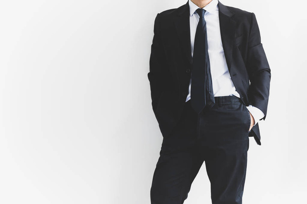 Hombre de negocios relajarse de pie con la mano en el bolsillo en frente de fondo blanco
 - Foto, imagen