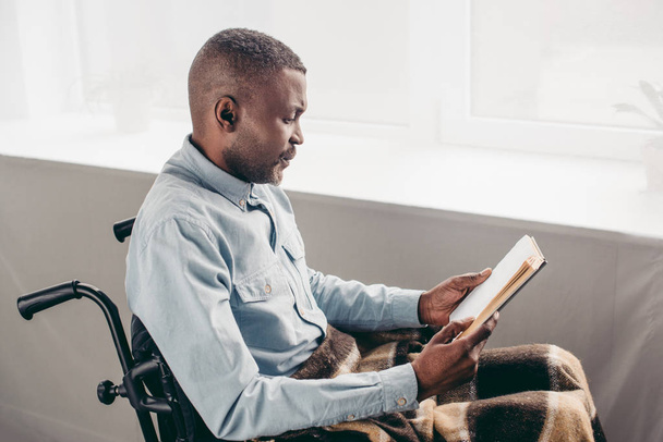 senior african american man in wheelchair reading book - Foto, Bild
