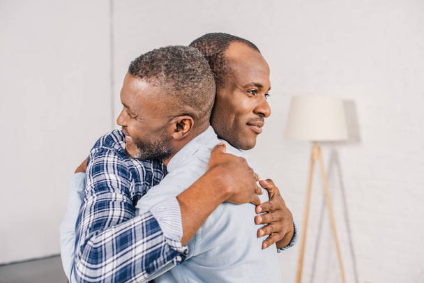 happy senior father and smiling adult son hugging at home  - Foto, imagen