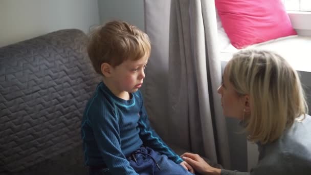 Upset little boy hugging his mother and crying at home - Materiał filmowy, wideo