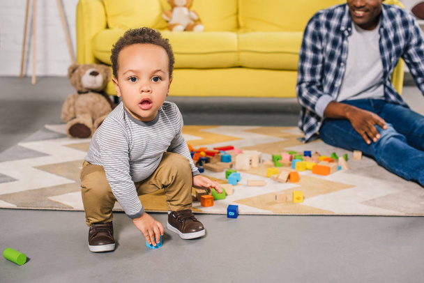adorable african american toddler looking at camera while playing with father at home - Foto, Bild