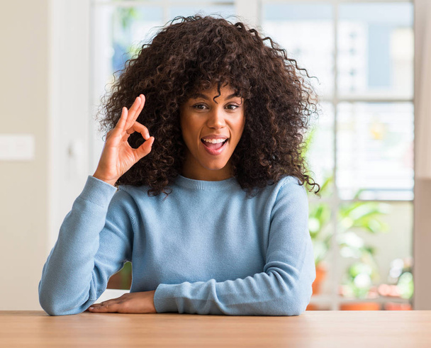 Africano americano mulher em casa sorrindo positivo fazendo ok sinal com a mão e os dedos. Expressão bem sucedida
. - Foto, Imagem