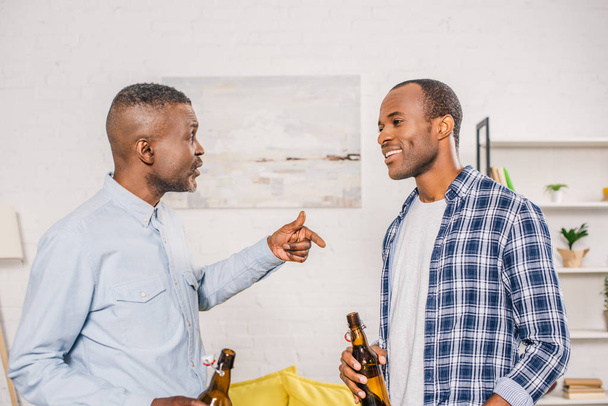 happy father with smiling adult son drinking beer and talking at home - Photo, Image