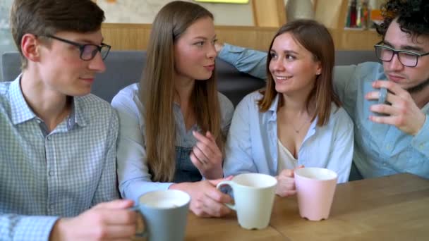 Jóvenes amigos se sientan en un café, toman café y se divierten comunicándose. Movimiento lento
 - Imágenes, Vídeo