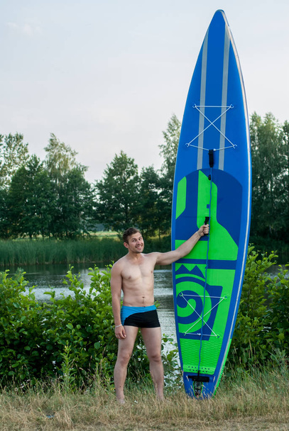 Un homme se tient sur le rivage et garde le SAP Board
, - Photo, image