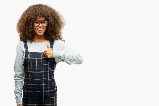 Africano americano mulher vestindo um estilo retro feliz com grande sorriso fazendo ok sinal, polegar para cima com os dedos, excelente sinal
 - Foto, Imagem