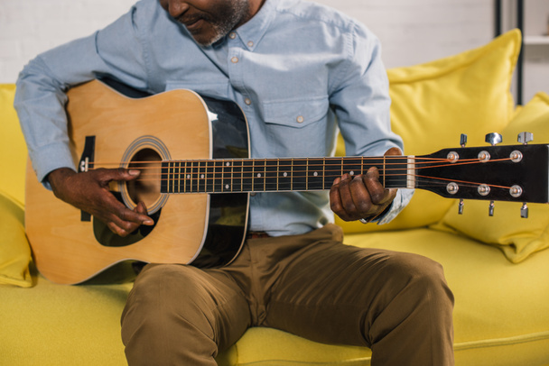 cropped shot of senior african american man playing acoustic guitar at home - Fotó, kép