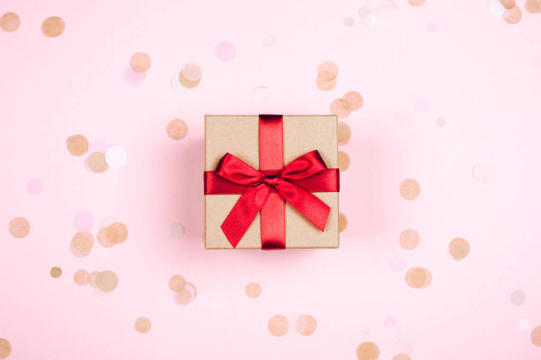 gift box with red bow on pink background with confetti - Fotoğraf, Görsel