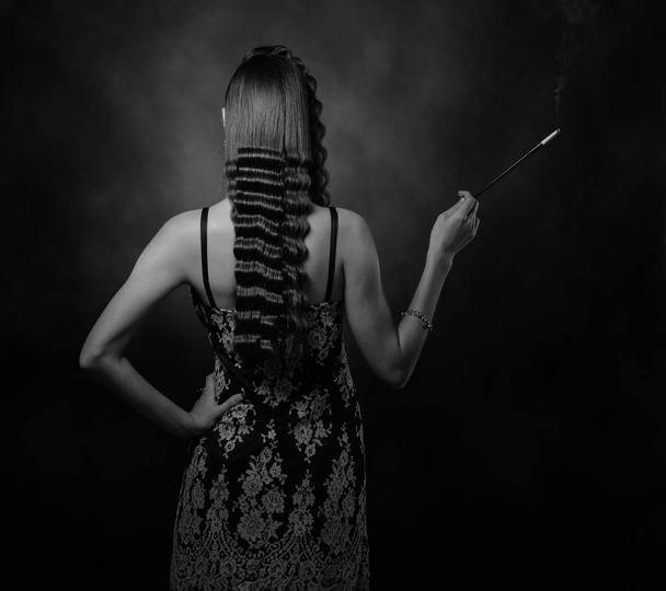 Beautiful woman with perfect long hair and makeup . Attractive girl with long mouthpiece on a black background . Studio shot . - 写真・画像
