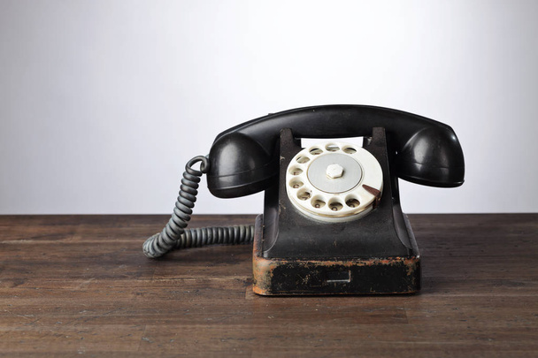 Oude zwarte telefoon op een houten tafel. Ruimte voor uw tekst kopiëren . - Foto, afbeelding