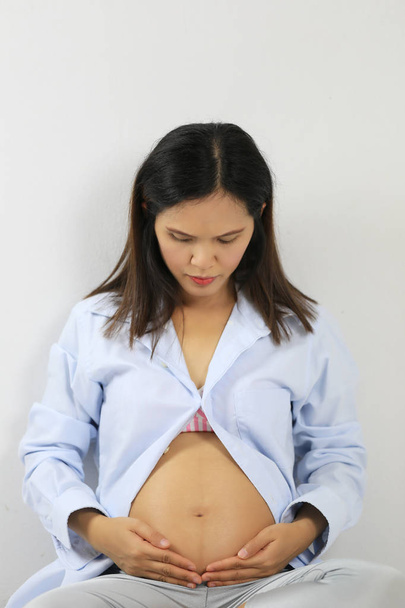 Ασίας έγκυος μητέρα σε μπλε φόρεμα με τη φωτογραφία του μωρού στο στομάχι υπέροχο πορτρέτο για το σχεδιασμό έννοια εργασία σας. - Φωτογραφία, εικόνα