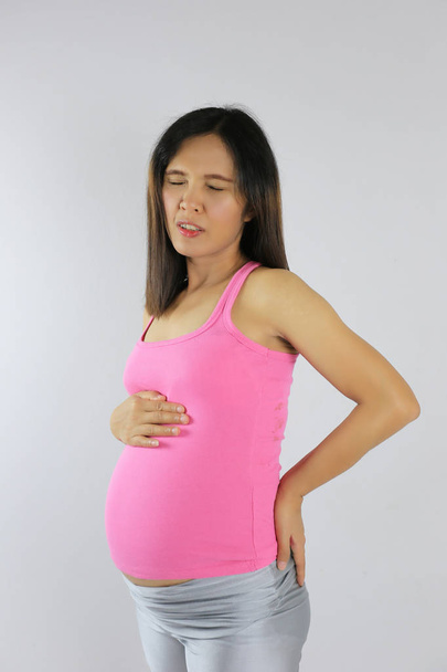 Asian pregnant women is a waist pain and use hand touch to stomach. - Фото, изображение