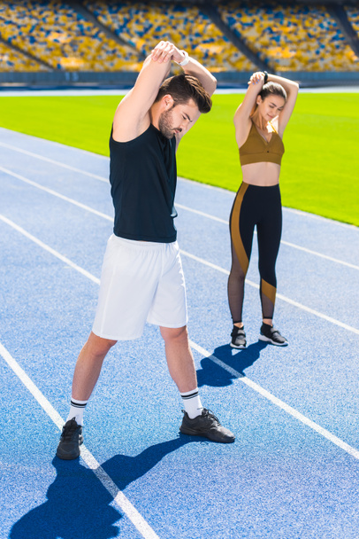 молодая пара спортсменов разогревается перед тренировкой на беговой дорожке на спортивном стадионе
 - Фото, изображение