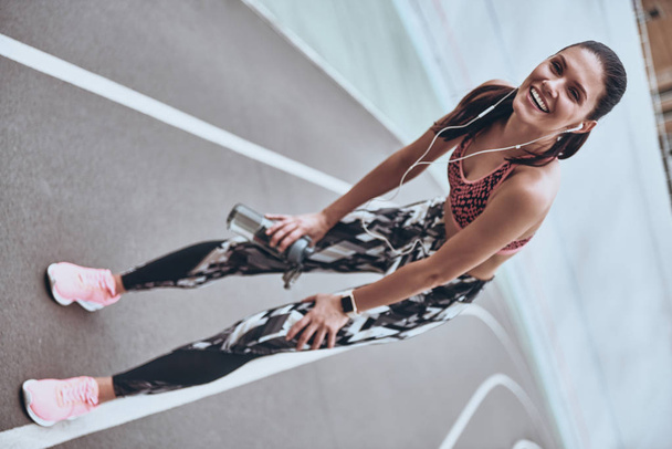 brunette woman resting on running track stadium and looking at camera with smile - Fotoğraf, Görsel