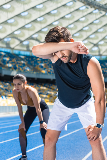young exhausted couple standing on running track at sports stadium after jogging - Photo, Image