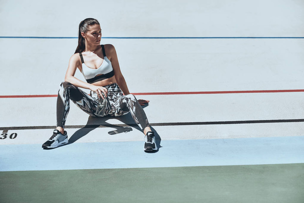 woman in sports clothing resting on running track stadium  - Zdjęcie, obraz