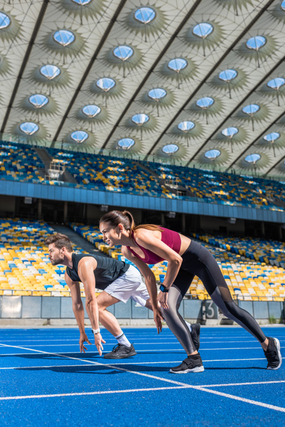 alkalmas fiatal férfi és női olimpiai bajnokok kezdő pozíciója a futópálya, sportcsarnok - Fotó, kép