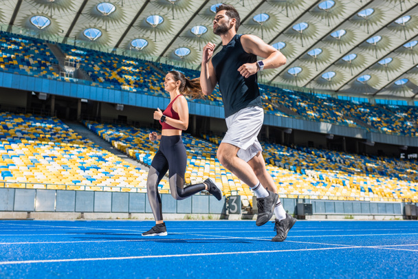 plan de mouvement de jeunes joggeurs masculins et féminins qui courent sur la piste au stade de sport
 - Photo, image