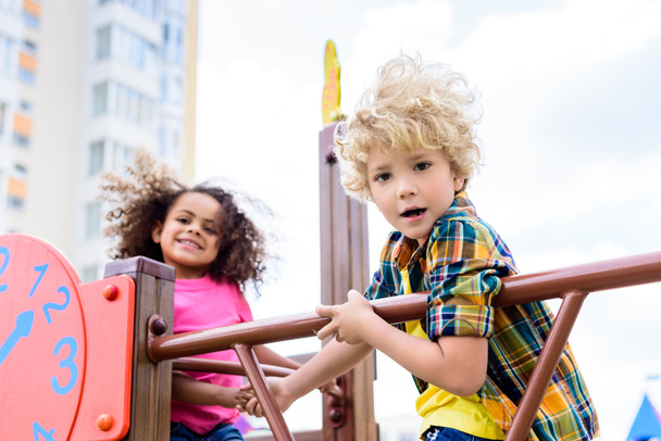 selective focus of two multiethnic little kids having fun at playground  - 写真・画像