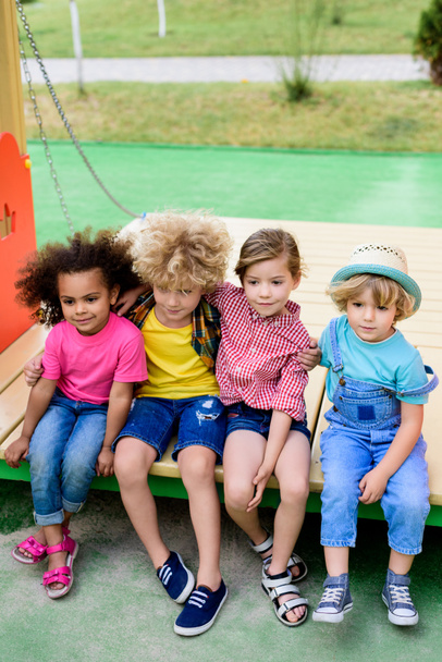 vista de ángulo alto del grupo multiétnico de niños adorables abrazándose en el patio de recreo
  - Foto, imagen