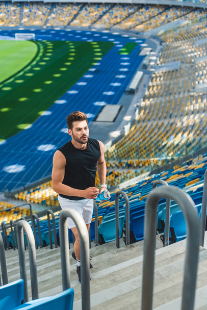 high angle view of handsome young man jogging upstairs at sports stadium - Photo, Image