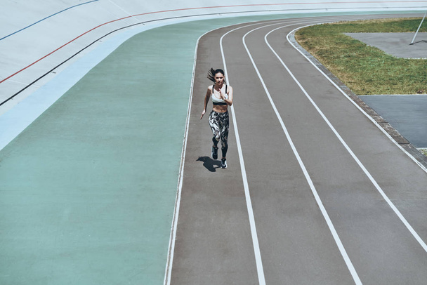 full length, top view of young woman in sports clothing running while exercising outdoors - Fotó, kép