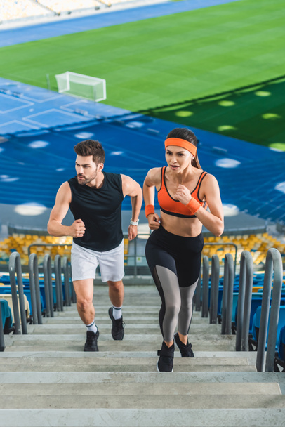 vista ad alto angolo di giovane coppia sportiva jogging al piano di sopra allo stadio sportivo
 - Foto, immagini