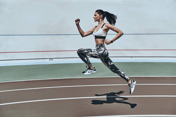 longitud completa de la mujer joven en ropa deportiva corriendo mientras hace ejercicio al aire libre
 - Foto, imagen