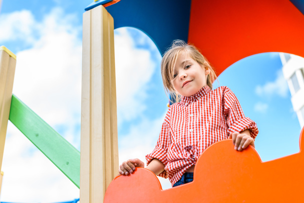низький кут зору усміхненої маленької дитини розважається на дитячому майданчику
  - Фото, зображення