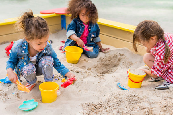 üç çok ırklı küçük çocuklar plastik kaşık toz ve kova ile oynarken sanal Bahçesi,  - Fotoğraf, Görsel