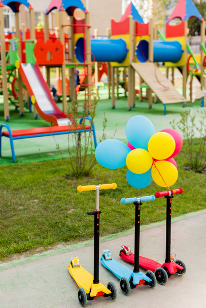 três scooters pontapé infantil colocados em linha com balões de ar coloridos no parque infantil
  - Foto, Imagem