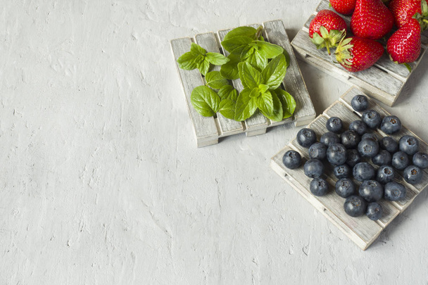 Fresh berries strawberries blueberries mint on a wooden stand, grey background with Copy space for text. - Φωτογραφία, εικόνα