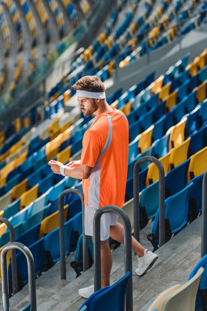 athletic young man walking downstairs on stairs at sports stadium - Foto, Imagem