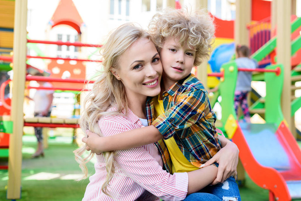 избирательный фокус счастливой матери, обнимающей очаровательного сына на детской площадке
  - Фото, изображение