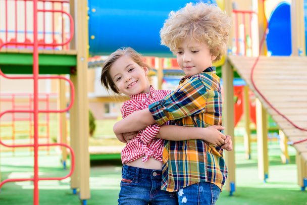 adorable little brother and sister embracing each other at playground  - Foto, Imagem