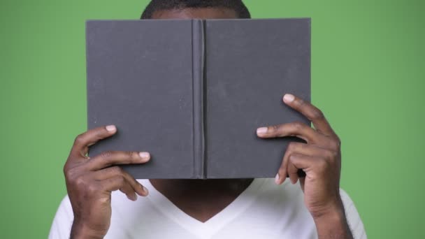 Young African man covering face with book - Metraje, vídeo