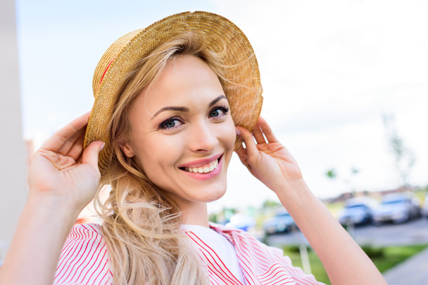 retrato de mujer joven sonriente en sombrero de paja sobre fondo borroso
  - Foto, Imagen