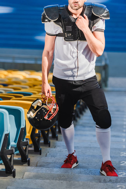 cropped shot of handsome young american football player standing on stairs at sports stadium - Φωτογραφία, εικόνα