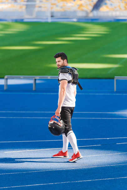 nuori amerikkalainen jalkapalloilija seisoo yksin urheilustadionilla
 - Valokuva, kuva