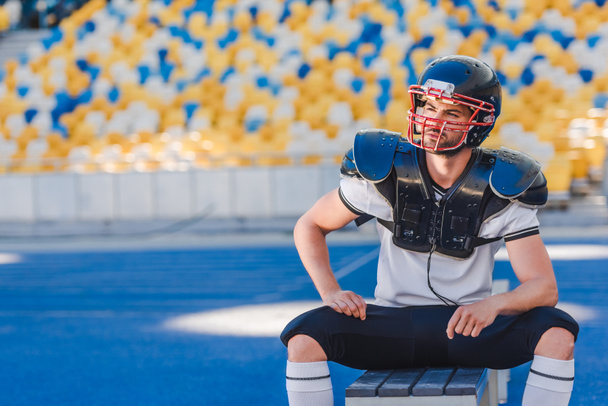 csinos fiatal amerikai-futball játékos ül a padon, a sport stadion - Fotó, kép